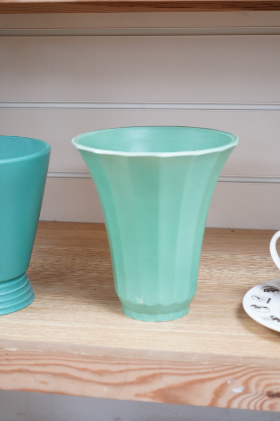 Keith Murray for Wedgwood, two green vases comprising a tapering, fluted example and one with stepped foot, largest 18cm high